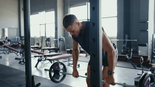 Man Weightlifting in Modern Gym with Fitness Equipment and Natural Light