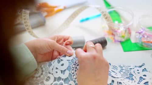 Close Up of Seamstress Hand Sewing Lace