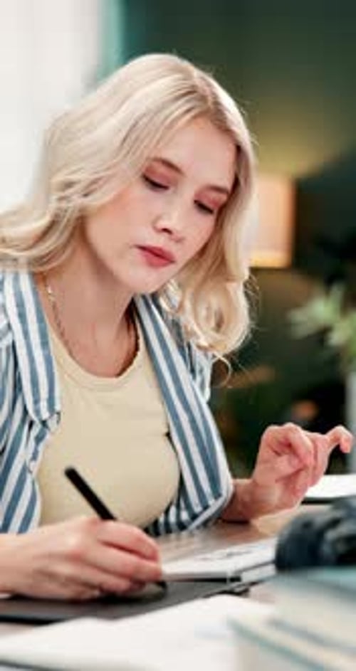 Young Woman Writes in Notebook at Her Desk