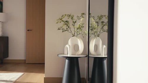 panning shot of a small side table with a plant a modern vase and a modern piece of art