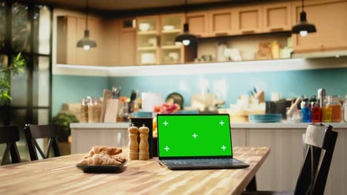 Green Screen Laptop on Wooden Table in Empty Bright Kitchen