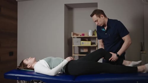 A Male Osteopath Performs Physical Therapy on a Female Patient The Doctor Looks at the Condition of