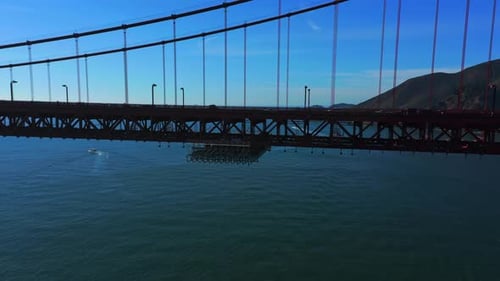 Aerial reveal of cars and trucks traveling on the San Francisco Golden Gate Bridge.