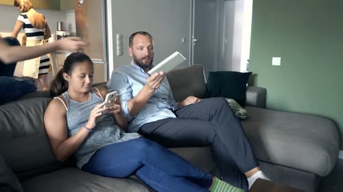 Family at home using electronics on the couch