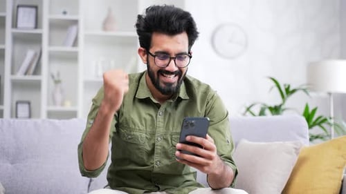 Man Reacts to Good News on Phone at Home