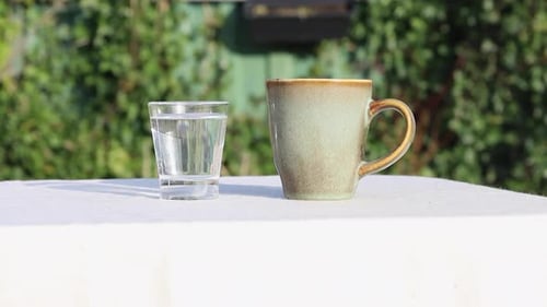 Pouring Milk into Mug Next to Glass of Water