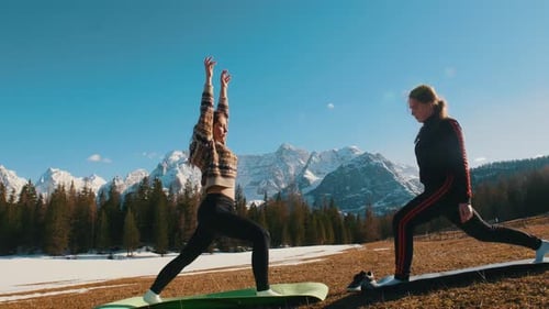 Two Young Healthy Women Doing Yoga Outside Mountains and Forest