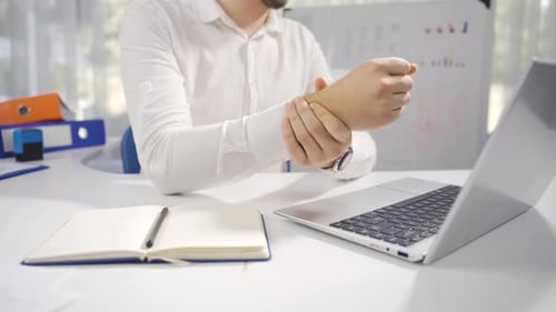 Adult Rubbing Wrist at Desk in Office