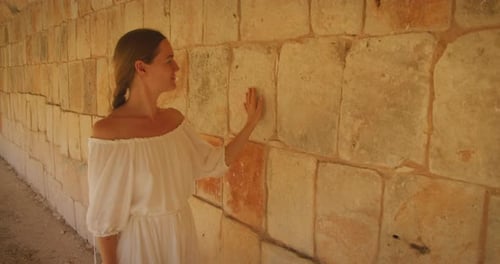 Woman touching ancient wall inside a stone corridor of Mayan ruins in Mexico