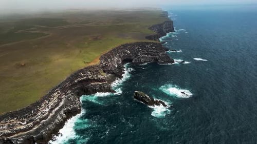 Aerial view of crispy waves breaking on the cliffs along the coastline in Iceland.