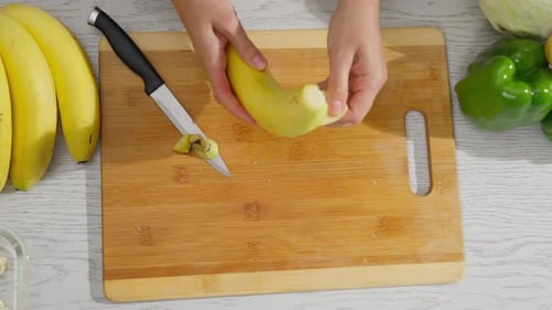 Hands peeling and slicing a banana on cutting board