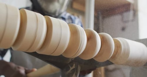 African american male carpenter wearing protective helmet turning wood on a lathe at carpentry shop