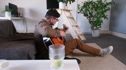 Young Adult Playing Guitar in Relaxed Indoor Setting