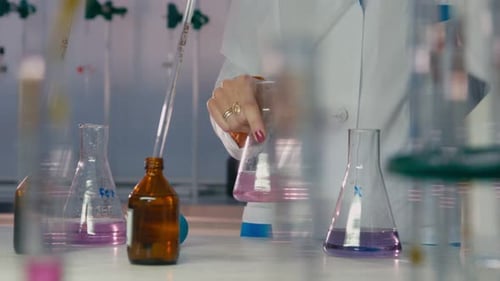 Mulher cientista pinga reagente na amostra líquida acima da tabela