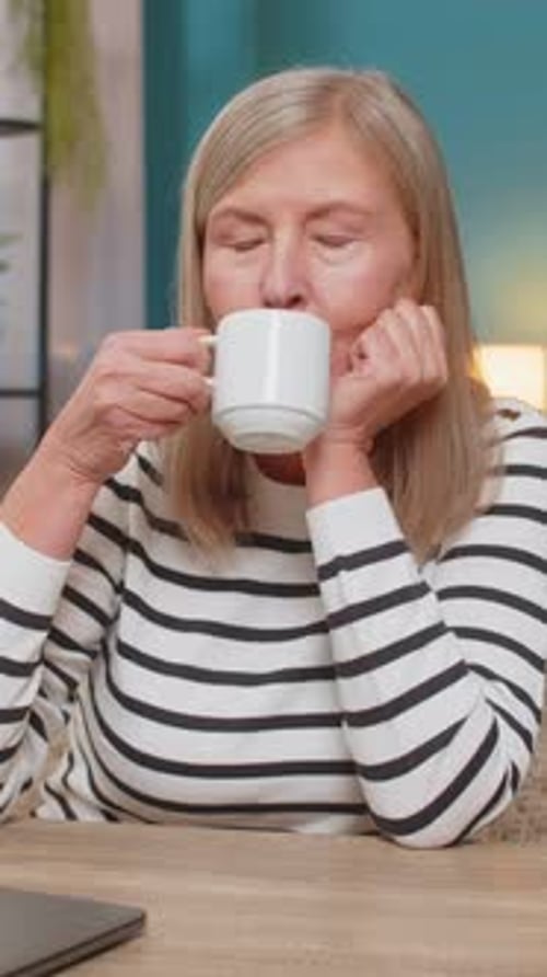 Mature Woman Happily Closing Laptop After Completing Important Task Smiling and Relaxing at Table