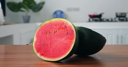 Closeup of Two Equal Halves of a Ripe Organic Green Watermelon on a Wooden Cutting Board on a