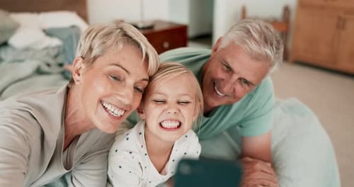 Grandparents and Grandchild Take Fun Selfie in Bed