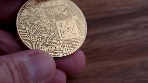 Le verso d'un Bitcoin physique conservé sur un fond en bois.