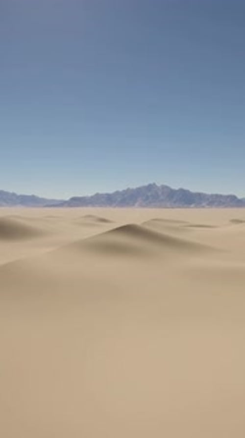A Desert Landscape with Sand Dunes and Mountains in the Distance