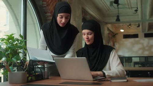 Women Collaborate on Laptop in Modern Urban Office