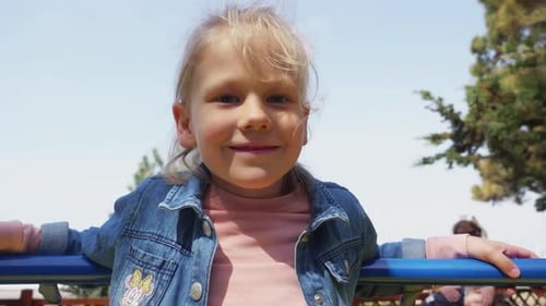 Little girl playing on a vintage blue merry-go-round on the playground