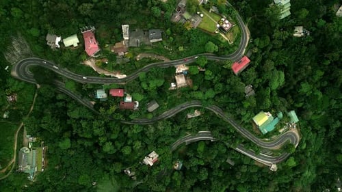 Aerial View Over Mountain Roads Weaving Through Green Forest in Sri Lanka Vehicles Navigate Tight