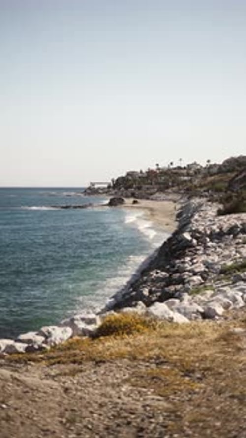 Scenic Coastal View with Rocky Shoreline and Distant Seaside Town