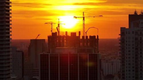 Tower Lifting Cranes at High Residential Apartment Building Construction Site at Sunset Real Estate