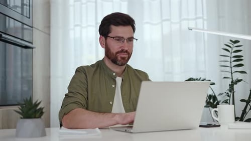Smiling Man Working at Laptop in Home Office