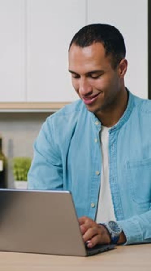 Smiling Man Uses Laptop Computer at Home