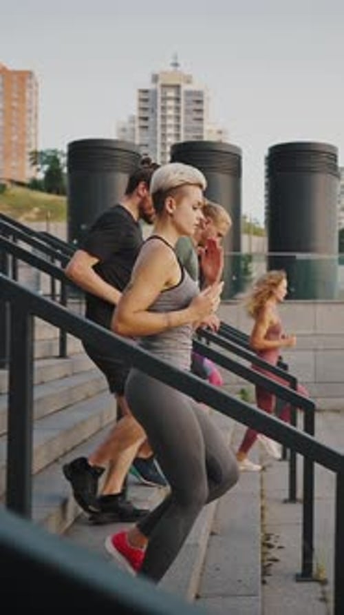 Young Men and Women a Mixed Race Company Dressed in Jerseys and Shoes Run Up the Outdoor Stairs in a