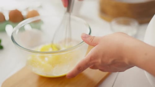 Eating, housewife parent engrossed in process stirs egg yolks with kitchen whisk at home kitchen