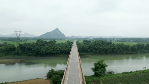 Drone Flying Over the Long Bridge That Crosses the Big River Between the Mountains of Vietnam