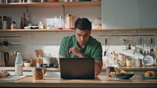 Man Working on Laptop and Eating Breakfast