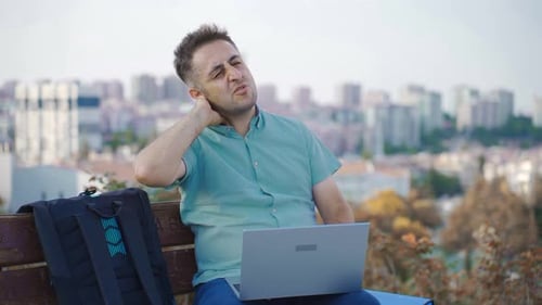 Man Works on Laptop, Massages Stiff Neck
