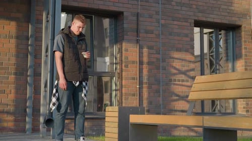 Junger Mann wirft Zigarette im Freien bei Tageslicht in den Mülleimer