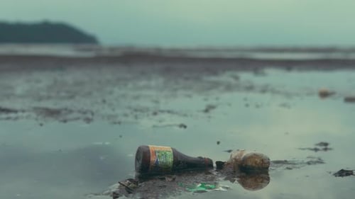Verschmutzungskrise: Verlassene Flaschen an einem ruhigen Strand bei Tagesanbruch