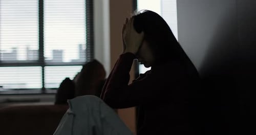 Woman Sitting on Floor in Dark Room