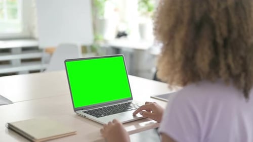 Young African Woman Using Laptop with Chroma Key Screen