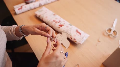 Woman prepares string to use for decoration a Christmas gift, close-up