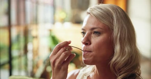 Woman with Blonde Hair Eats Food Indoors