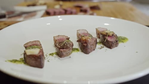 Chef Carefully Garnishing Sliced Steak on a Plate