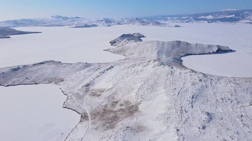 Captivating Aerial View of a Snowcovered Rocky Landscape Surrounding a Frozen Lake
