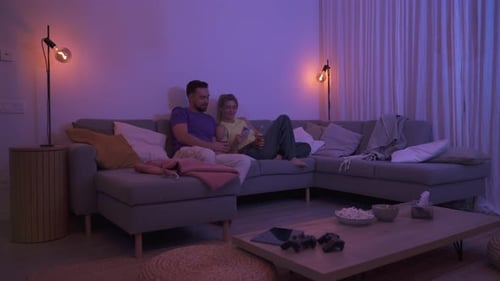 Couple Relaxing on Couch, Using Phone in Living Room