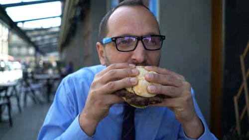 Hungry Businessman Eating Burger in Cafe 30s