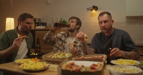 Trio of Happy Guys Friends Eating Pizza and Drinking Beer During Bachelor Party at Home in the