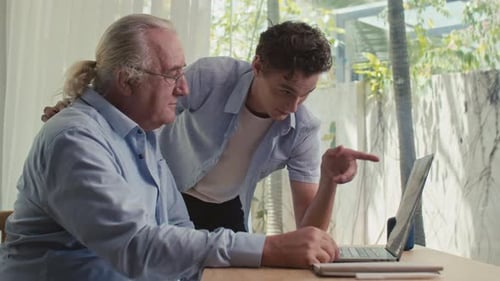 Young Adult Helping Senior with Laptop Computer at Home