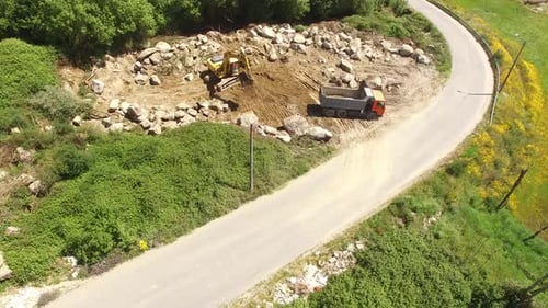 Bagger, der Sand in einen Muldenkipper transportiert. Szene. Ansicht von oben auf den Bagger, der Sand in den LKW lädt. Const
