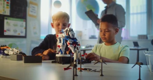 Elementary School Students Studying Model of Innovative Robotic Arm in Group in Classroom