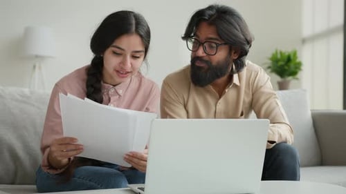 Adults Collaborating on Laptop with Documents at Home